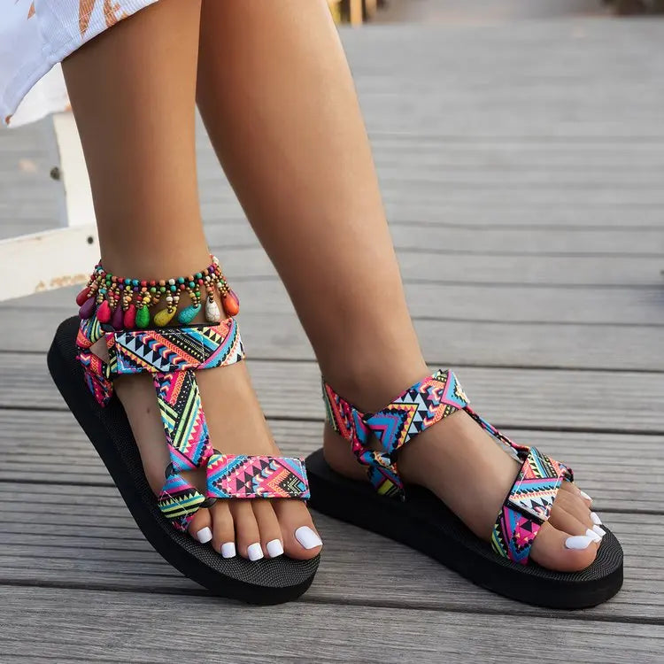 Femme portant une sandale plate à lanières scratch multicolores avec une robe blanche – tenue estivale joyeuse